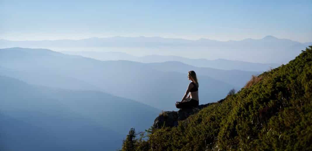 sporty young woman meditating in mountains.