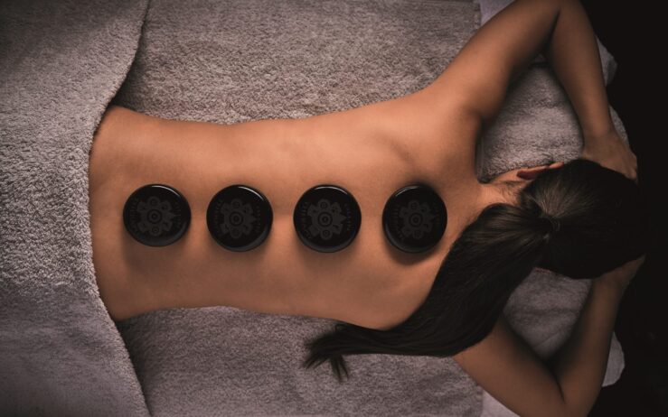 spa wellness treatment obsidian massage mood model frau auf liege mit steinen auf ruecken straubinger bad gastein